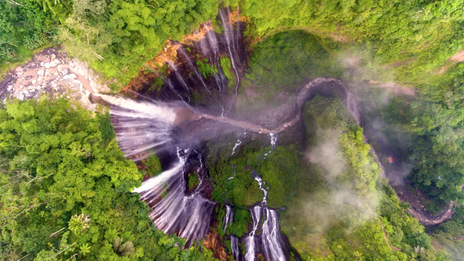 Tumpak Sewu waterfall cascading down lush green cliff in East Java Indonesia